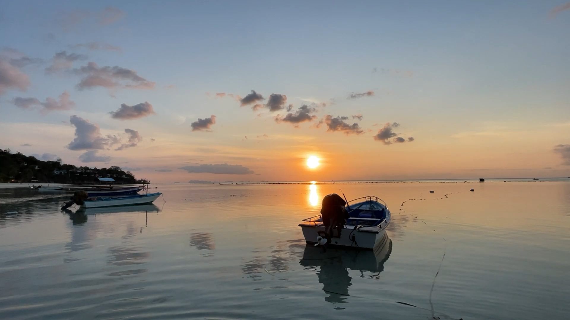 Calm sea at sunset with a small boat resting on the water